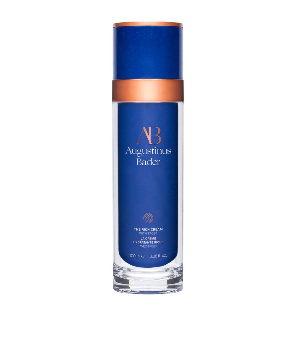 A blue and white bottle of Augustinus Bader The Rich Cream with a copper-colored cap.