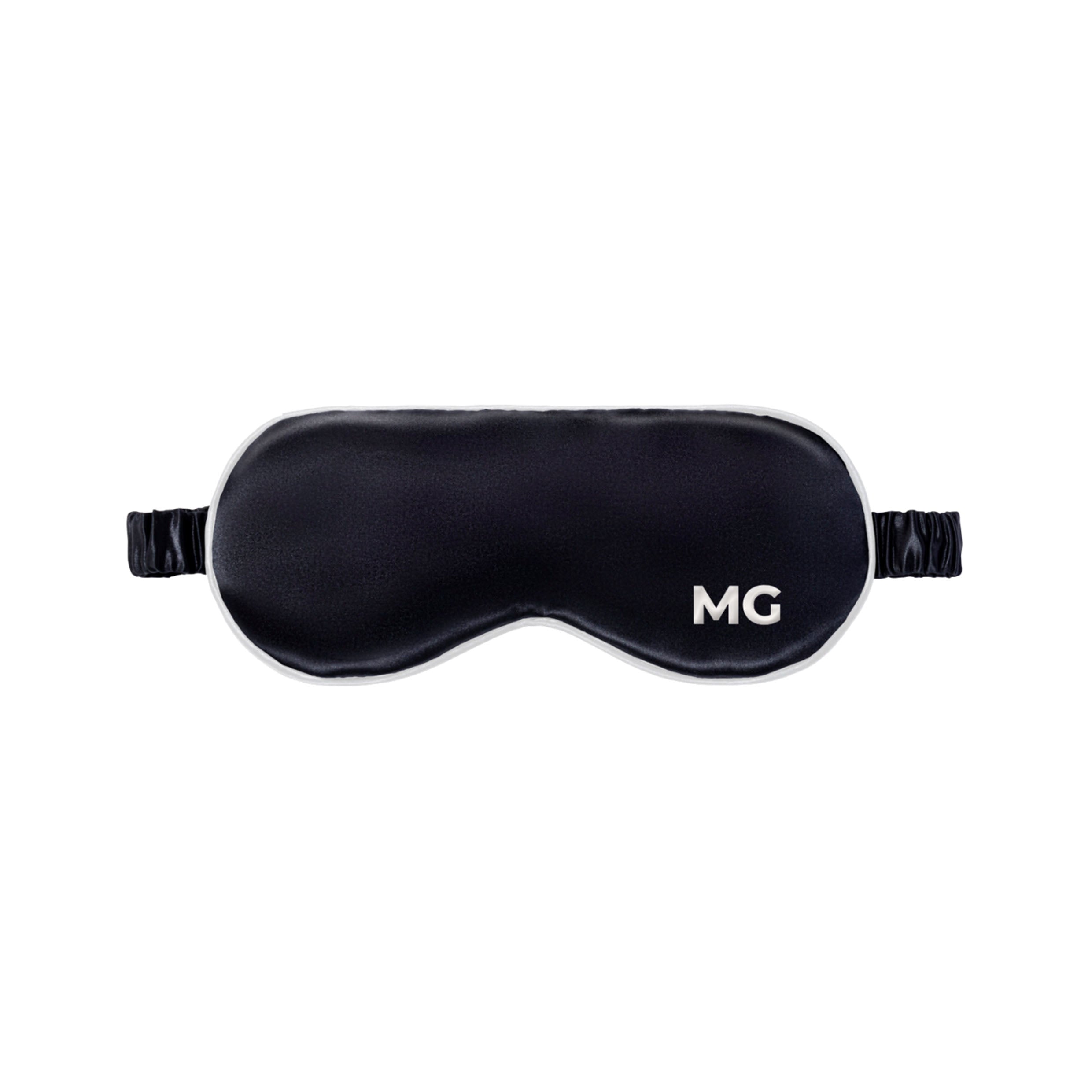 A black silk sleep mask with the initials 'MG' embroidered on the front.