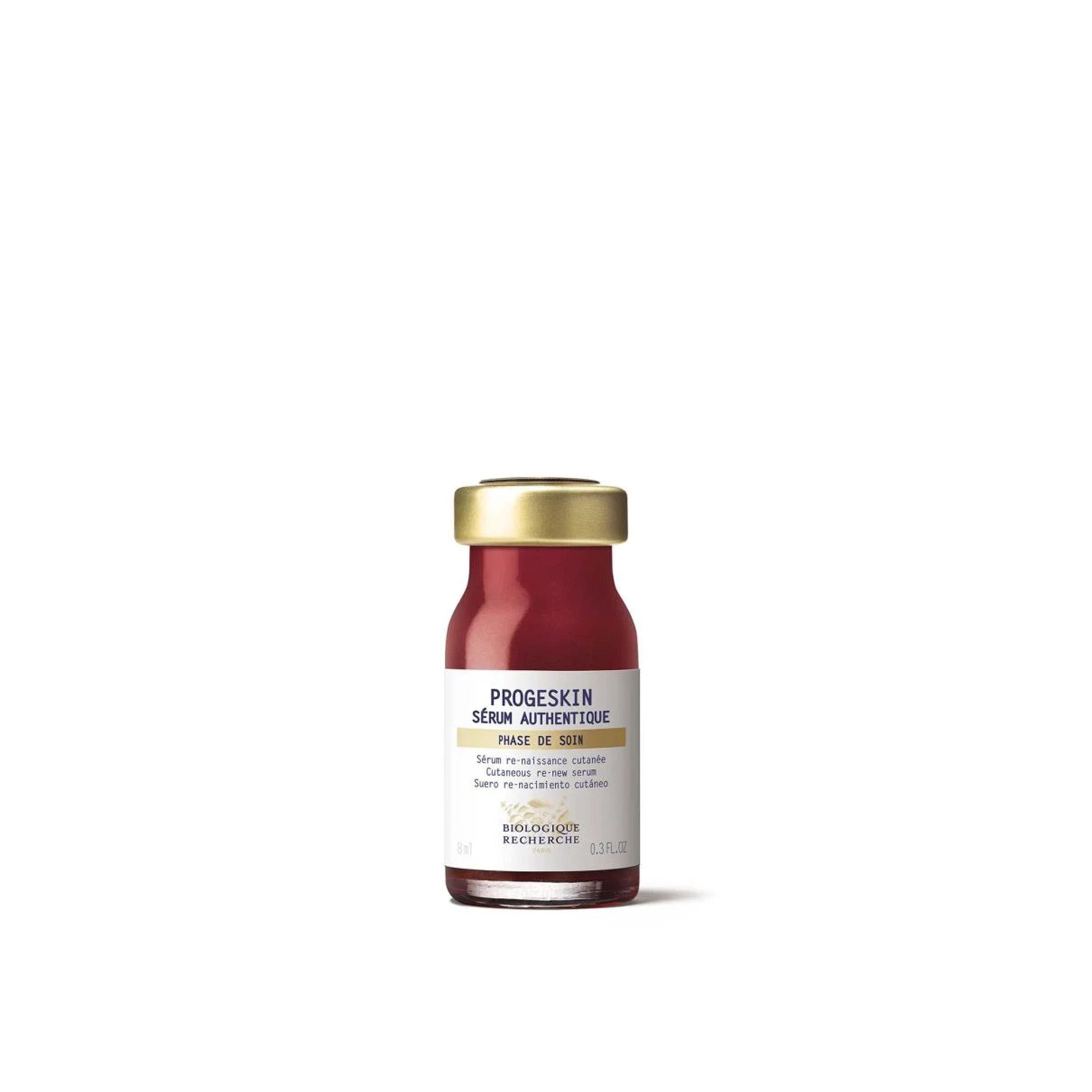 Skincare serum bottle with gold cap and white label on a white background