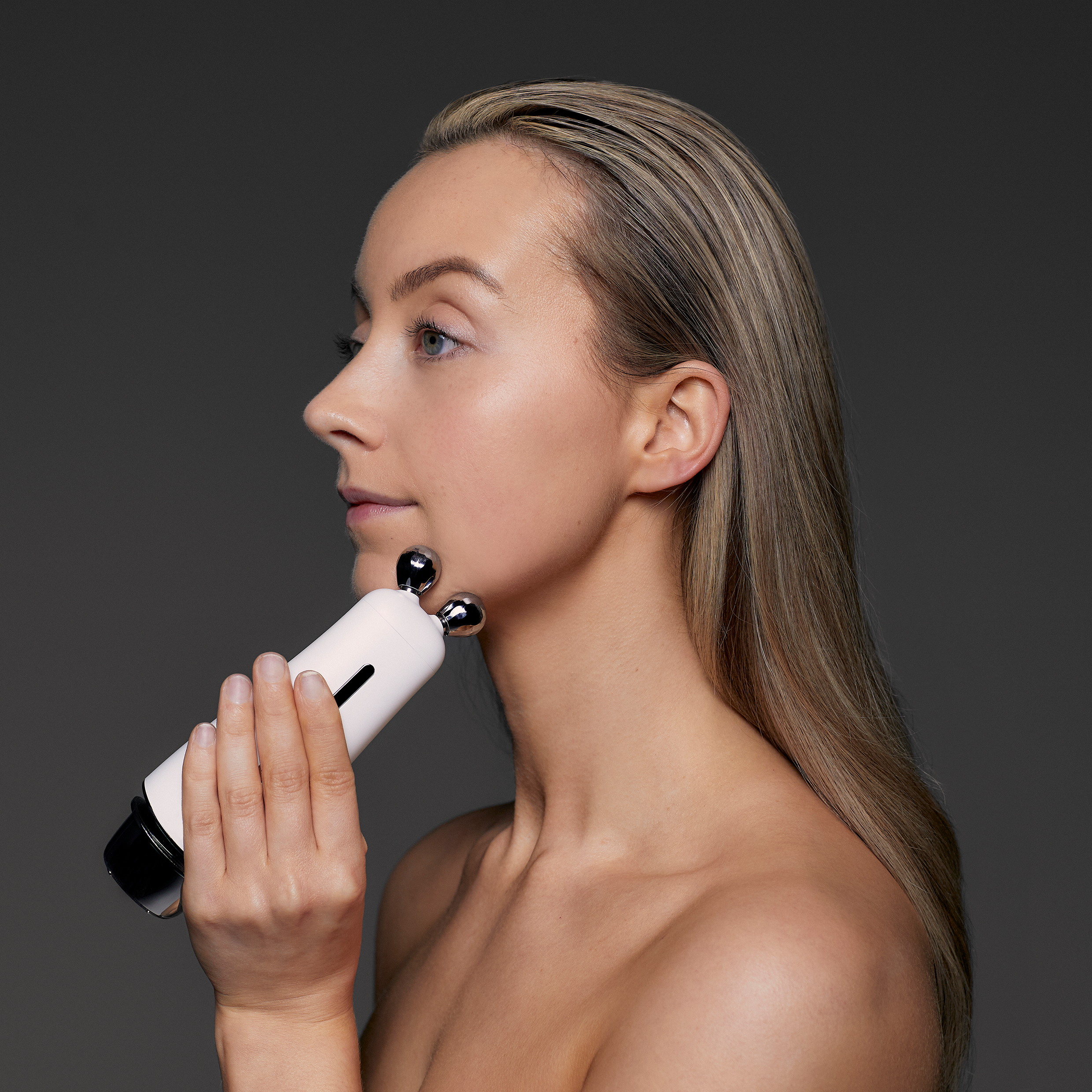 A model holding a skincare devuce to her chin