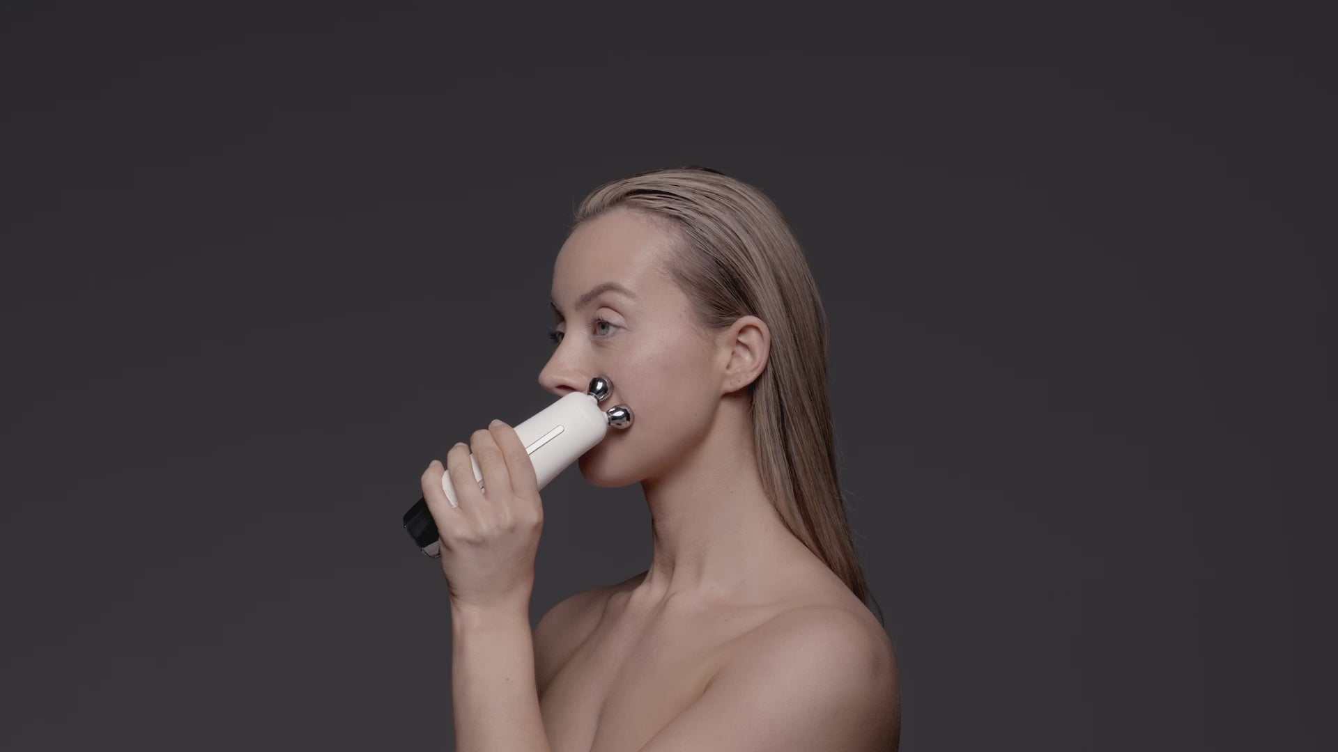 A model using a facial device called the Sculpta on the left side of her face.