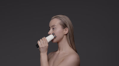 A model using a facial device called the Sculpta on the left side of her face.