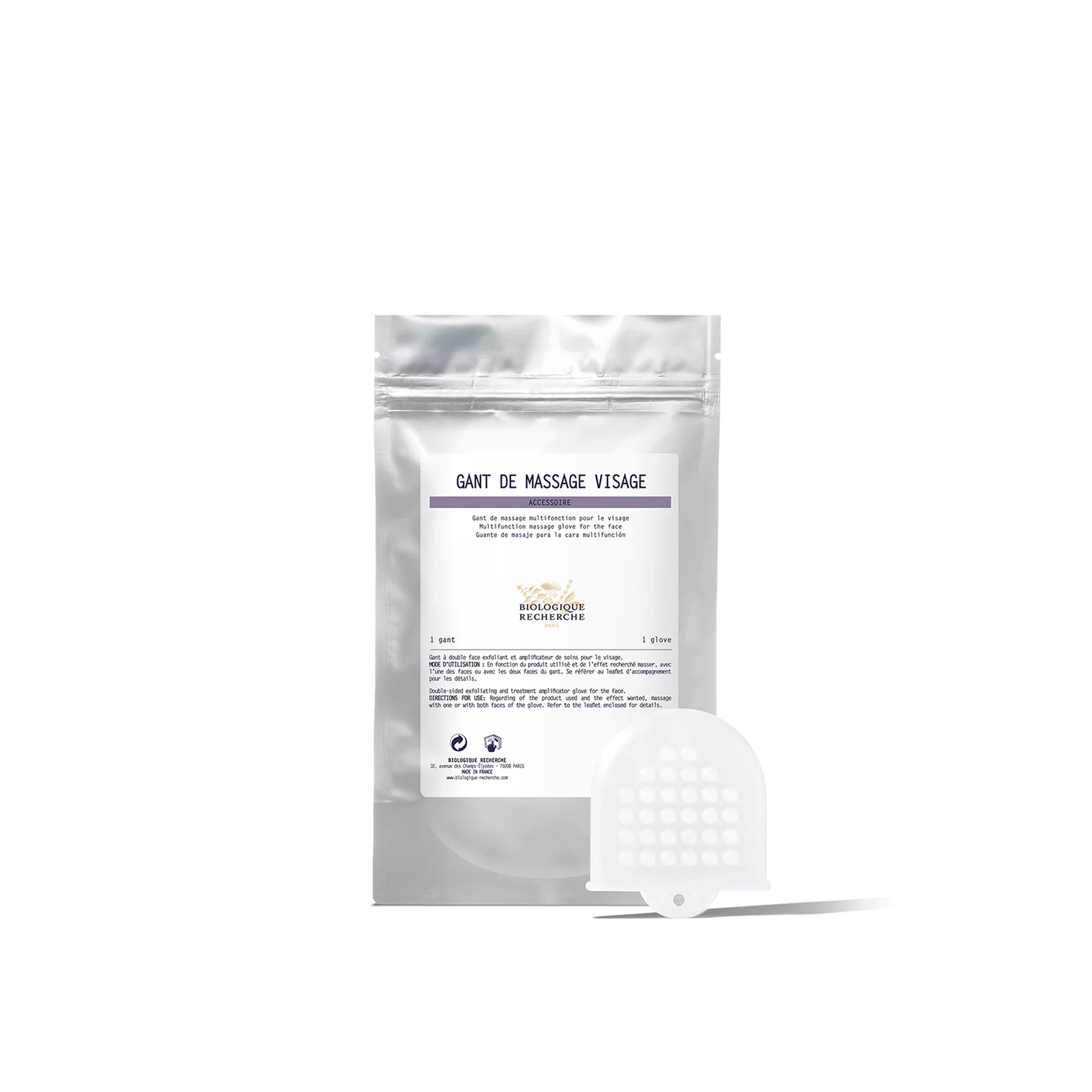 A packaged facial massage glove with a white and purple label, and an additional white glove with a textured surface lying in front.