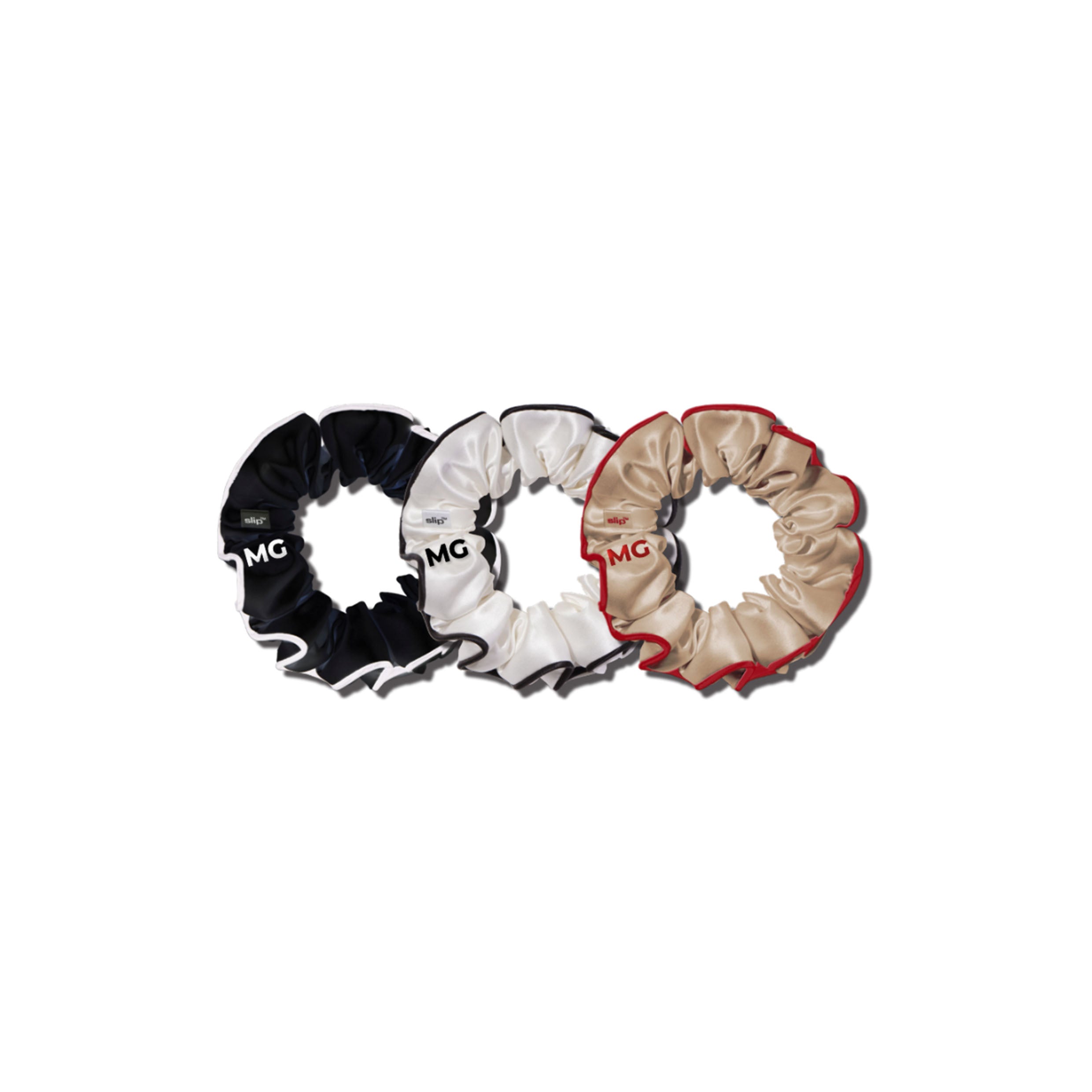 Three multi large scrunchies in black, white, and beige colors, arranged in a circular pattern with the 'MG' logo visible on each.